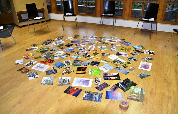 Fotos liegen auf einem Holzboden in einem Raum mit Stühlen und Fenstern.