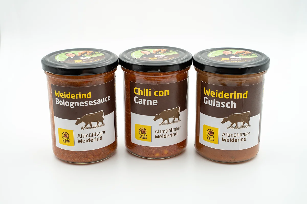 Drei Gläser mit Weiderind Bolognesesauce, Chili con Carne und Weiderind Gulasch vor weißem Hintergrund.