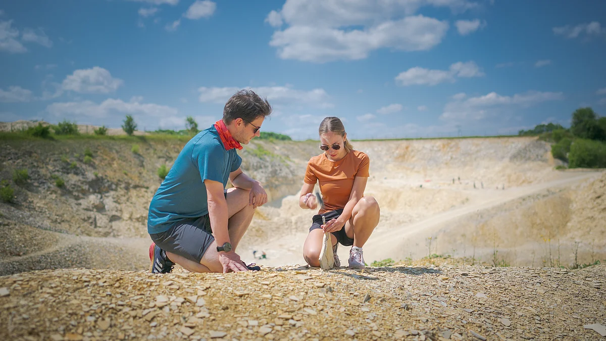 Fossilien suchen im Steinbruch Blumenberg Zwei Personen knien auf einem steinigen Gelände und untersuchen den Boden.