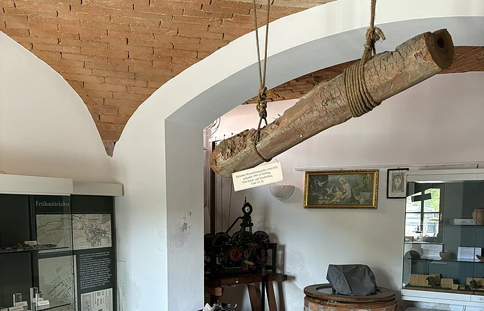 In einem gemauerten Gewölbe stehen Vitrinen an den Wänden. Von der Decke hängt ein alter Balken