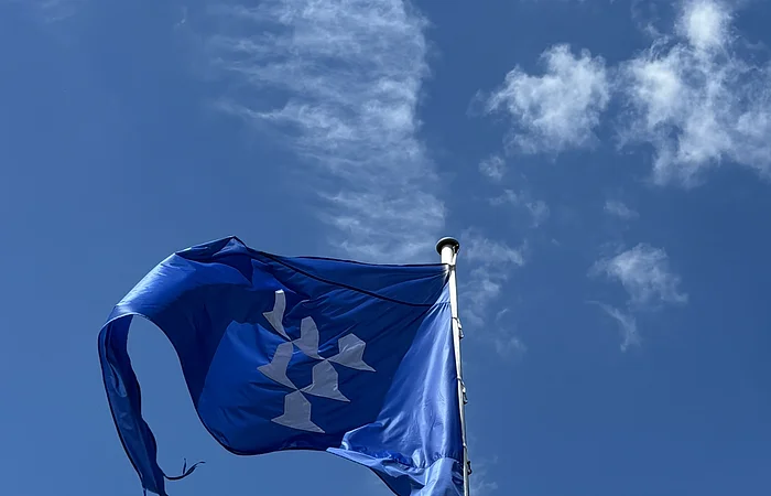 Vor einem blauen Himmel mit wenigen Wolken ist die blaue Flagge der Burg Pappenheim zu sehen.