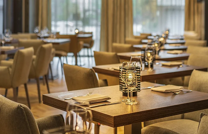 Restaurant mit gedeckten Tischen, Stühlen und Kerzenlicht in warmem Ambiente