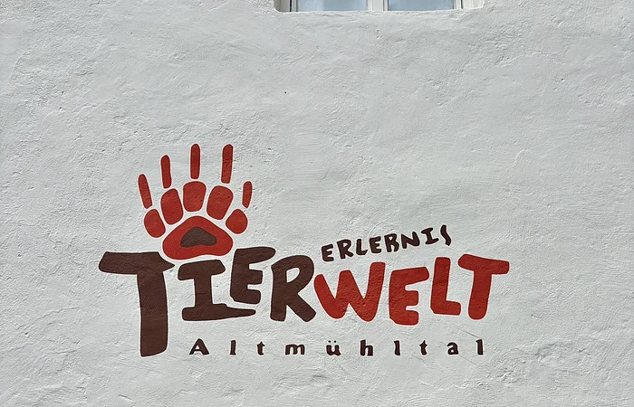 das Logo der Erlebnistierwelt Altmühltal ist auf einer Hauswand zu sehen. Das Logo hat die Farben Rot und Braun