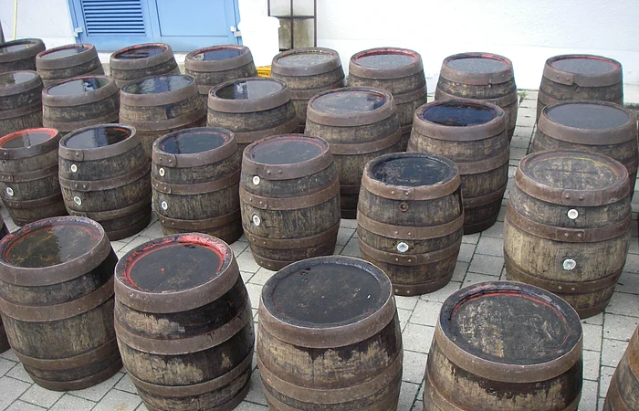 Ein Anzahl an Holzfässern steht auf gepflastertem Grund