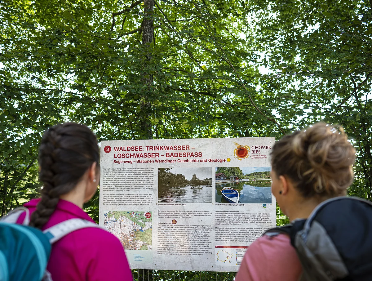 Zwei Freundinnen lesen die Informationstafel "Sagenweg" am Waldsee.