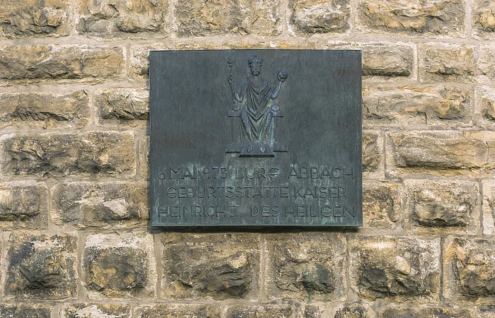 Bronzetafel an einer Steinmauer mit der Aufschrift zur Geburtsstätte Kaiser Heinrich II. in Bad Abbach.