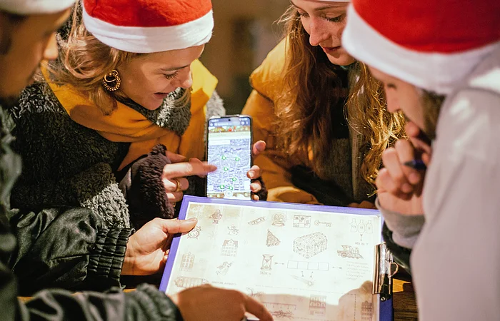 Vier Frauen mit Weihnachtsmützen lösen ein Rätsel