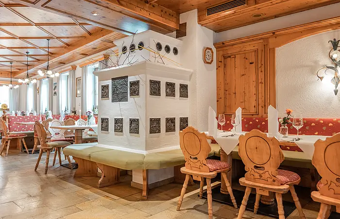 Traditionell bayerische Gaststube der Krone in Kinding. Eingerichtet mit einem typisch bayerischen gemauerten Kamin und Sitzmöglichkeiten drum herum sowie viele Holzelemente (Holzdecke, Teilvertäfelung an den Wänden, Holzstühle).