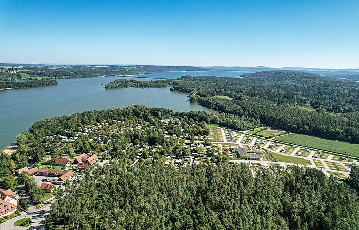 Ein Luftbild des Brombachsees. Der See ist umgeben von Wald. Im vorderen Teil des ein Campingplatz.