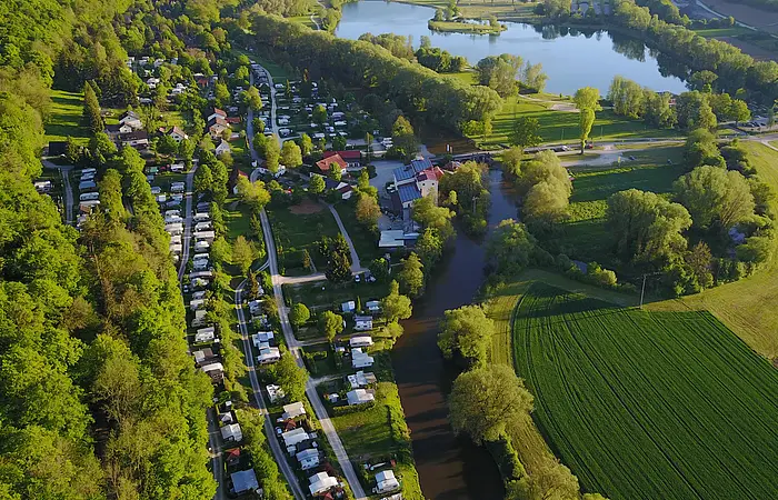 Der Campingplatz Kratzmühle mit vielen Wohnmobilen, -wagen von oben gesehen. Der Platz ist ein wenig in den Hang eingebettet und rechts ist schon der Kratzmühlsee.