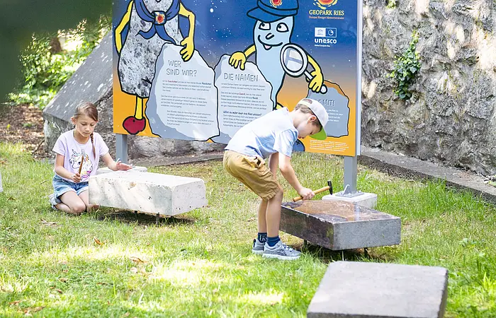 Kinder spielen an der Kinder-Erlebnisstation am Kreuzgraben mit Klangsteinen.