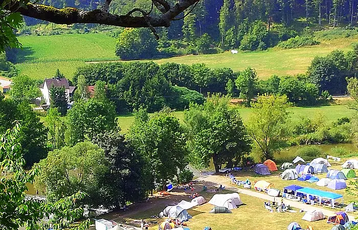 Der Zeltplatz von oben eingebettet in grün mit lauter bunten Zelten auf dem Platz verteilt.