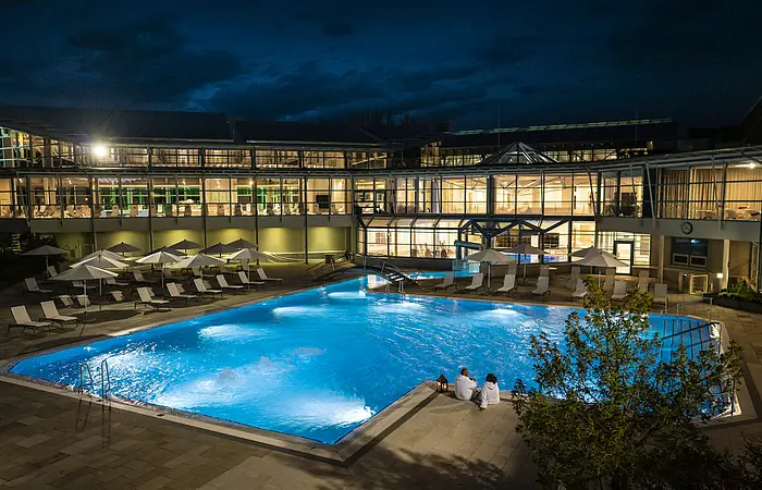 beleuchtetes Außenbecken der Therme bei Nacht