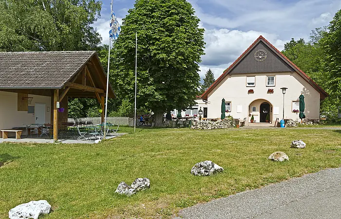 Das Naturfreundehaus von außen mit Hütte rechts und grüner Wiese im Vordergrund.