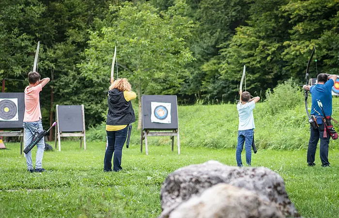 Eine Familie steht mit Pfeil und Bogen auf einer Wiese.