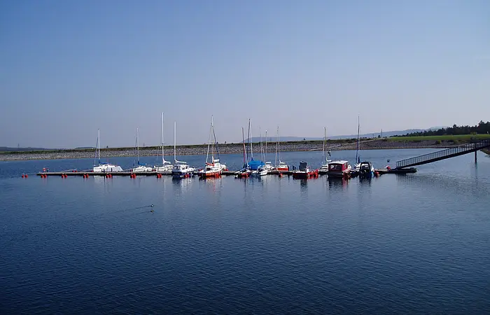 Ein Segelhafen im blauen See. Nur wenige Boote liegen im Hafen.
