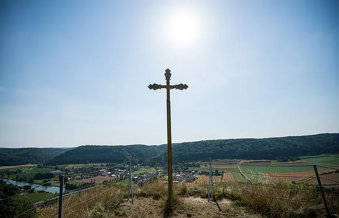 Auf dem Flügelsberg steht ein Kreuz dahinter hat man einen wunderschönen Blick ins Tal. Der Himmel ist wolkenlos.