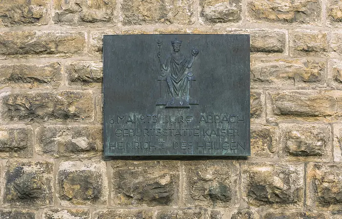 Bronzetafel an einer Steinmauer mit der Aufschrift zur Geburtsstätte Kaiser Heinrich II. in Bad Abbach.