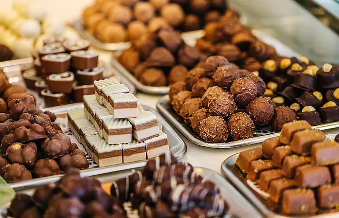 Verschiedene Pralinen auf Tellern. Die Pralinen sind mit Schokolade in verschiedenen Mustern verziert.