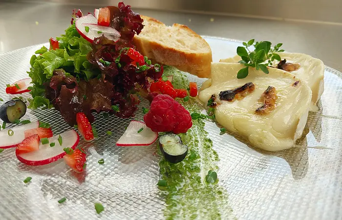 Ein Teller mit Ziegenkäse, Gemüse und ein paar scheiben Brot wird serviert