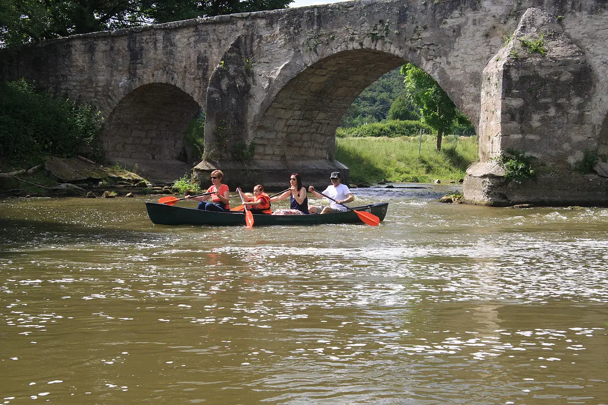 Bootsfahrer an der Steinbrücke bei Pfünz. Eine Familie ist einem Kanu vom Schmidt Bootsverleih auf der Altmühl unterwegs. Sie sind gerade unter der Steinbrücke hindurchgefahren, diese ist in Teilen noch zu sehen.