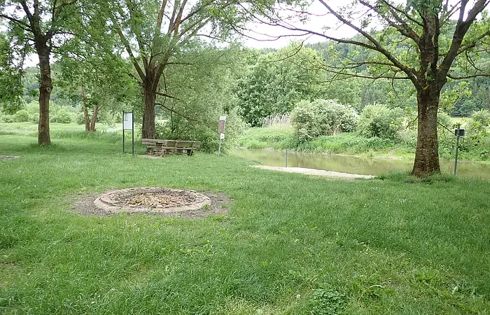 Der Bootsrastplatz direkt an der Altmühl ist eine grüne Wiese mit einigen Bäumen als Schattenspender. Es gibt einige Feuerstellen und Sitzgelegenheiten.
