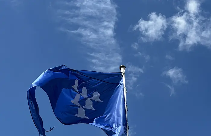 Vor einem blauen Himmel mit wenigen Wolken ist die blaue Flagge der Burg Pappenheim zu sehen.