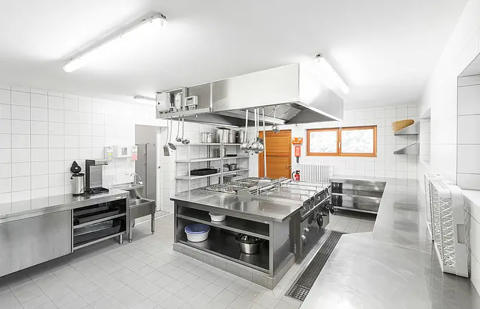 Die Großraumküche des Zeltplatzes ist in weiß und metall schlicht gehalten.