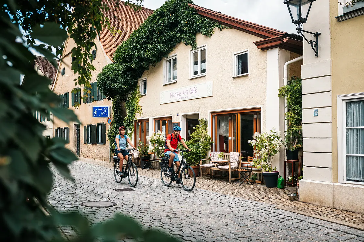 Radler fahren durch Pappenheim Zwei Radler mit blauem und rotem Shirt fahren durch die Altstadt Pappenheims.