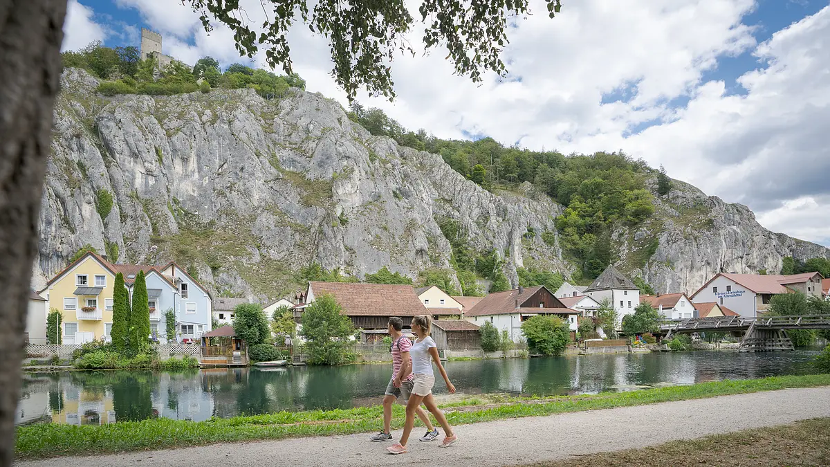 Wanderpärchen auf dem Altmühltal-Panoramaweg bei Essing Ein Pärchen spaziert entlang des Ludwig-Donau-Main-Kanals. Im Hintergrund ist der Ort Essing und seine Felsen zu sehen.