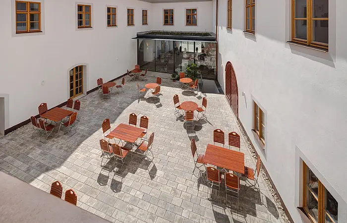 Blick in den Innenhof der Post Berching von oben auf ein gemütliches Ambiente mit Stühlen und Tischen eine Art Biergarten.