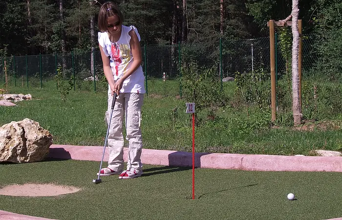 Auf dem Family Golfplatz im Seezentrum Heuberg am Rothsee spielt ein Mädchen hingebungsvoll Minigolf auf einem grünen Platz.