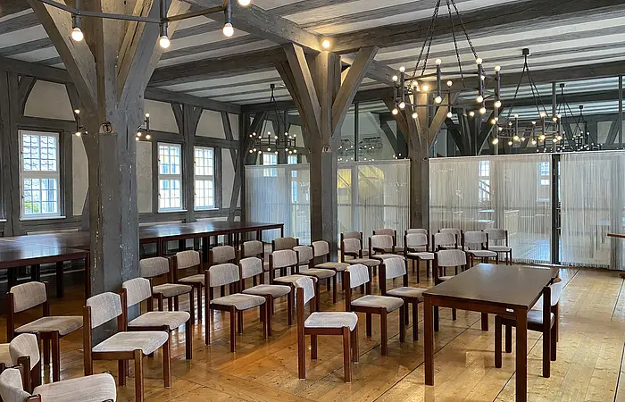 Blick in einen festlich beleuchteten Saal mit Holzboden und historischem Ambiente.