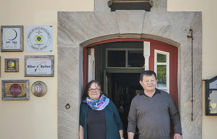 Ehepaar Hollberg, Wirtsleute stehen im Türbogen am Eingang ihres Gasthofes