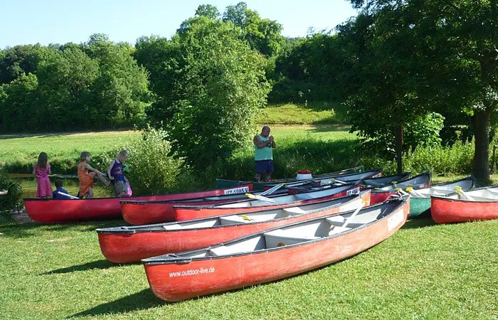 Mehrere rote Kanus liegen auf der Wiese am Zelt- und Bootsrastplatz Treuchtlingen