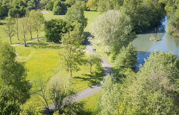 Luftaufnahme der Altmühl durch den Kurpark. In der Ferne laufen zwei Personen auf dem Weg.