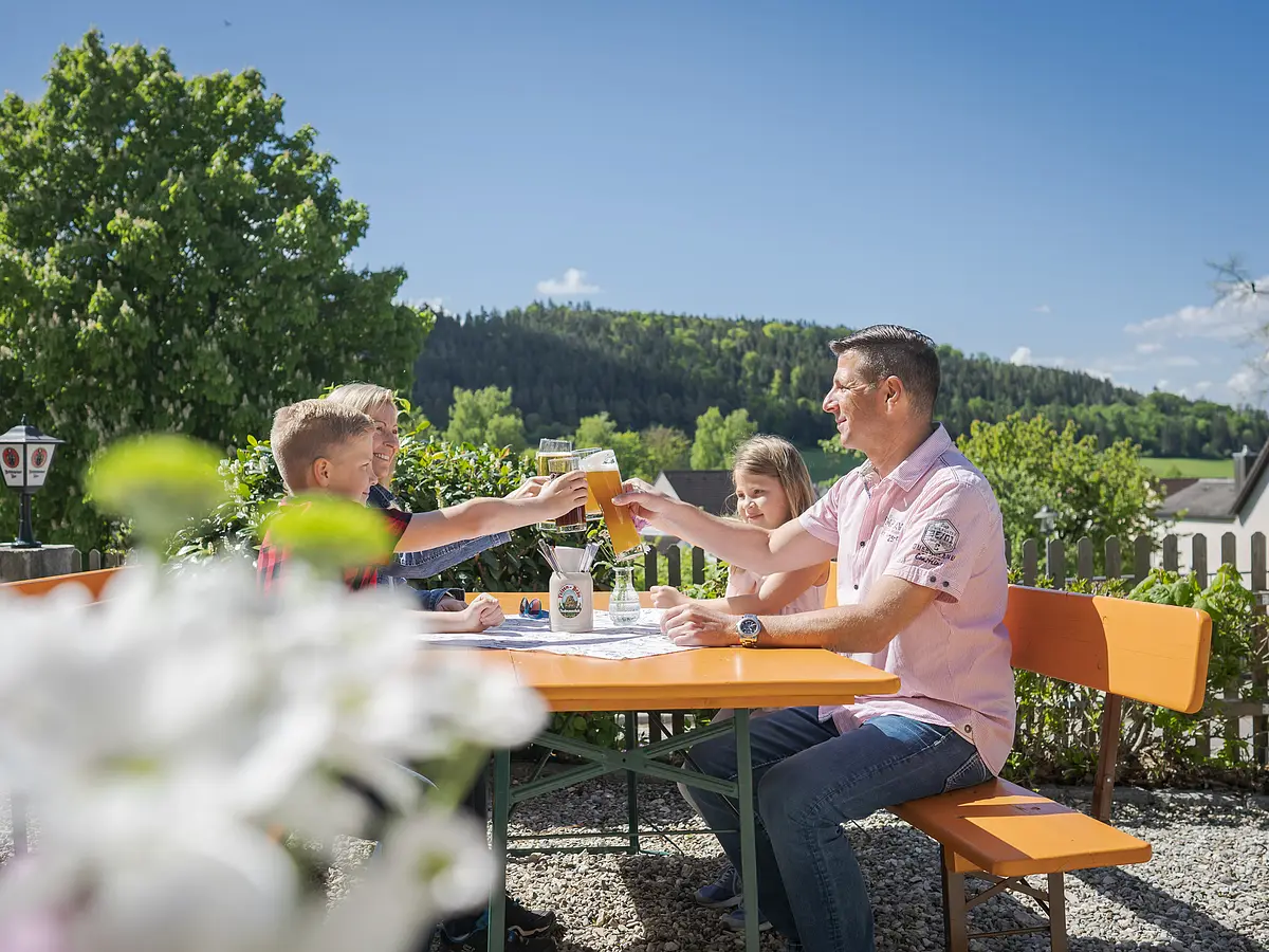 Wirtshaus Güldener Ritter - 8 Biergarten, Familie mit zwei jüngeren Kindern prostet sich zu, Blume und Umgebung mit Aussicht