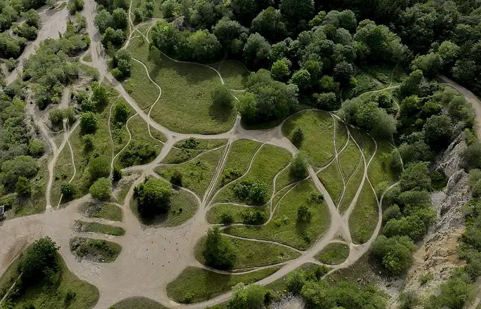 Luftbild eines Endurparks. Durch grüne Wiesen mit Bäumen schlängeln sich braune Wege.