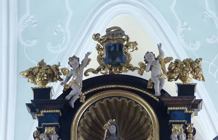 Barockes Altarretabel mit goldener Skulptur und Putten, verziert mit floralen Elementen und Engelsköpfen.