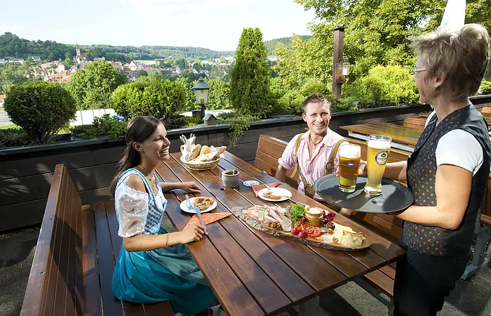 Das Foto zeigt den Biergarten des Hotel-Restaurant Bauer-Keller. Im Hintergrund sieht man einen Ausblick auf Greding.