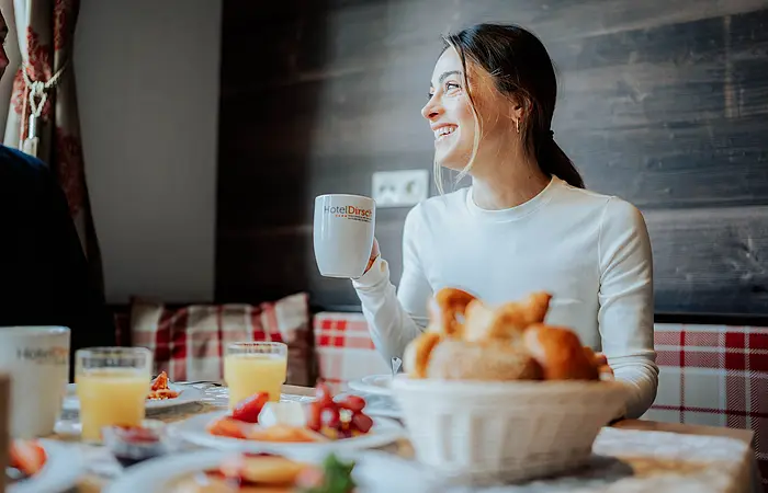 eine Frau sitzt an einem Tisch, der reichlich mit Angeboten vom Frühstücksbuffet gefüllt ist.