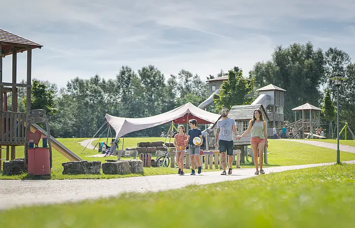 Eine Familie spaziert durch den Erlebnisspielplatz in Wald