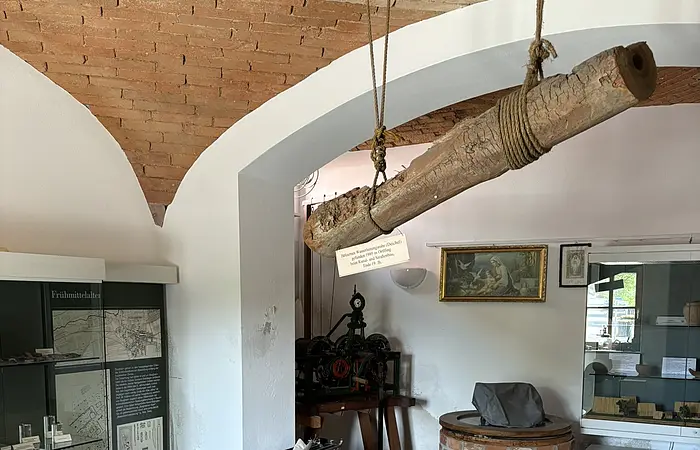 In einem gemauerten Gewölbe stehen Vitrinen an den Wänden. Von der Decke hängt ein alter Balken
