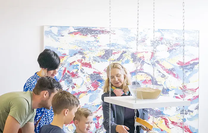 Eine Familie macht eine Führung im KunstMuseum und sieht sich bestimmte Gesteine an.