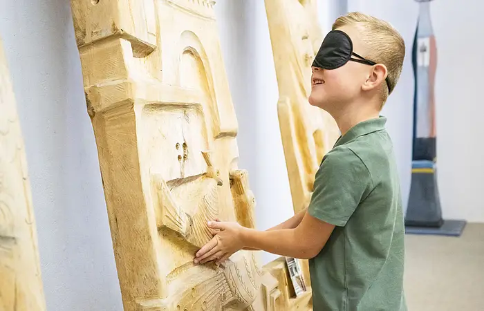 Ein Junge fühlt ein Kunstwerk mit seinen Händen und verschlossenen Augen.