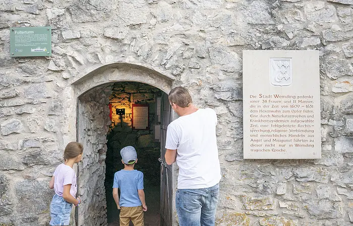 Vater betrachtet den Eingang des Folterturms mit seinen zwei Kindern.