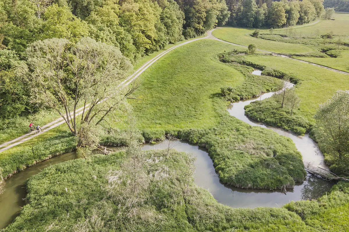 Radfahrer fahren entlang des Möhrenbachs, der Fluss schlängelt sich aus der Vogelperspektive