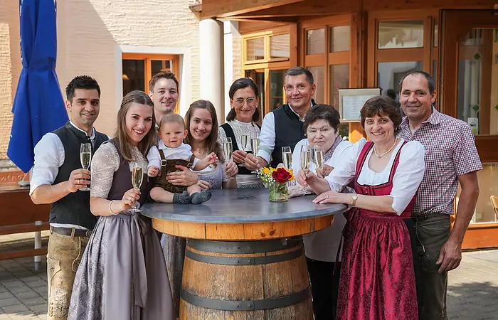 Das gesamte Team des Landgasthofes Euringer ist in Tracht gekleidet und steht hinter einem Stehtisch mit einem Glas Bier in der Hand.
