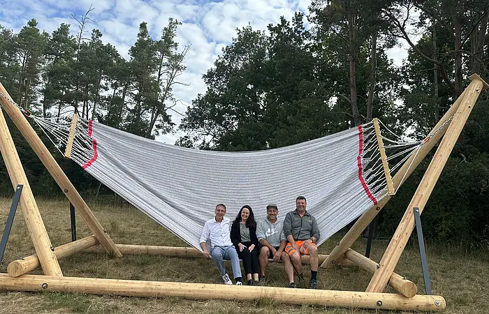 vier Erwachsene sitzen am Rand der Hängematte