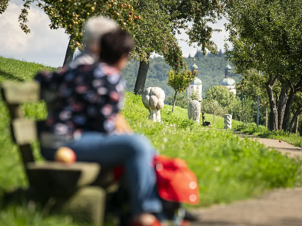 Andachtsweg zur Wallfahrtsbasilika Maria Brünnlein Ein Ehepaar sitzt auf einer Bank am Andachtsweg.